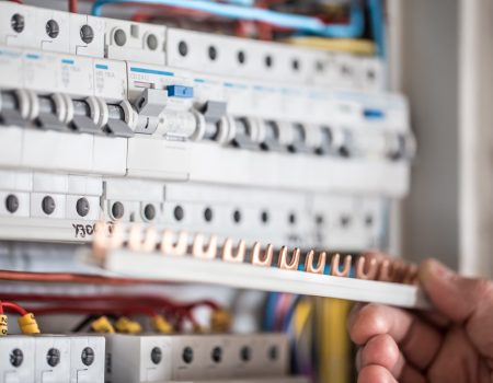 Man, an electrical technician working in a switchboard with fuses. Installation and connection of electrical equipment. Close up. Man, an electrical technician working in a switchboard with fuses. Installation and connection of electrical equipment. Professional with tools in hand. concept of complex work, space for text.